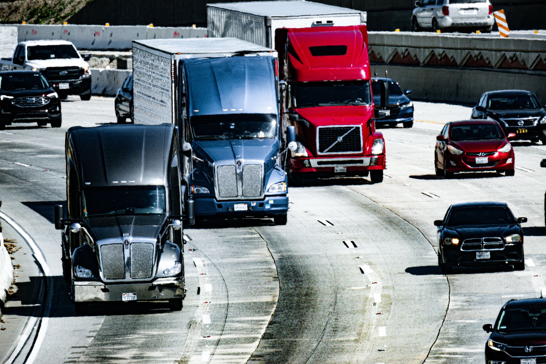 American semi trucks carrying freight along a busy urban highway