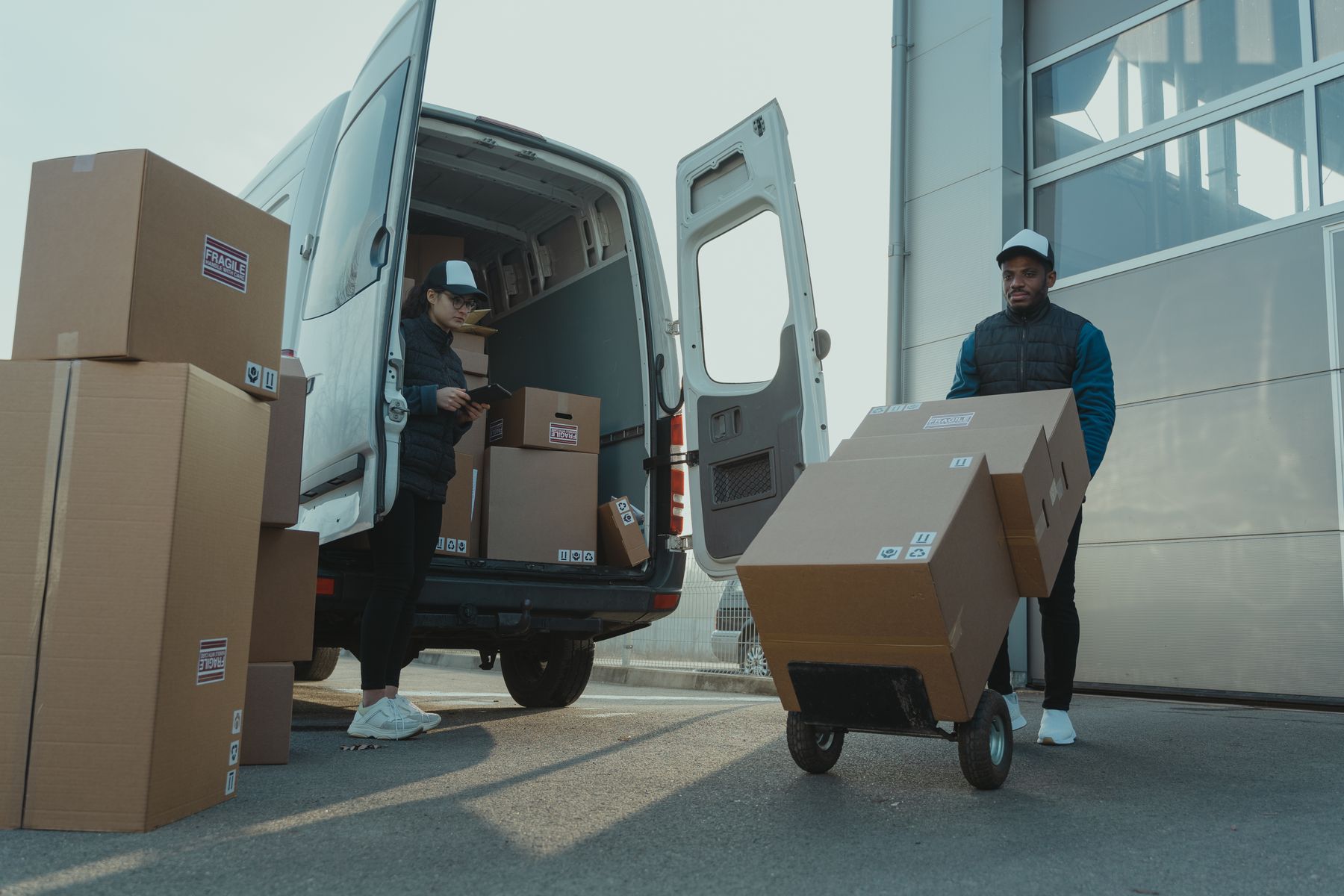 Two delivery workers loading cardboard cartons into a van
