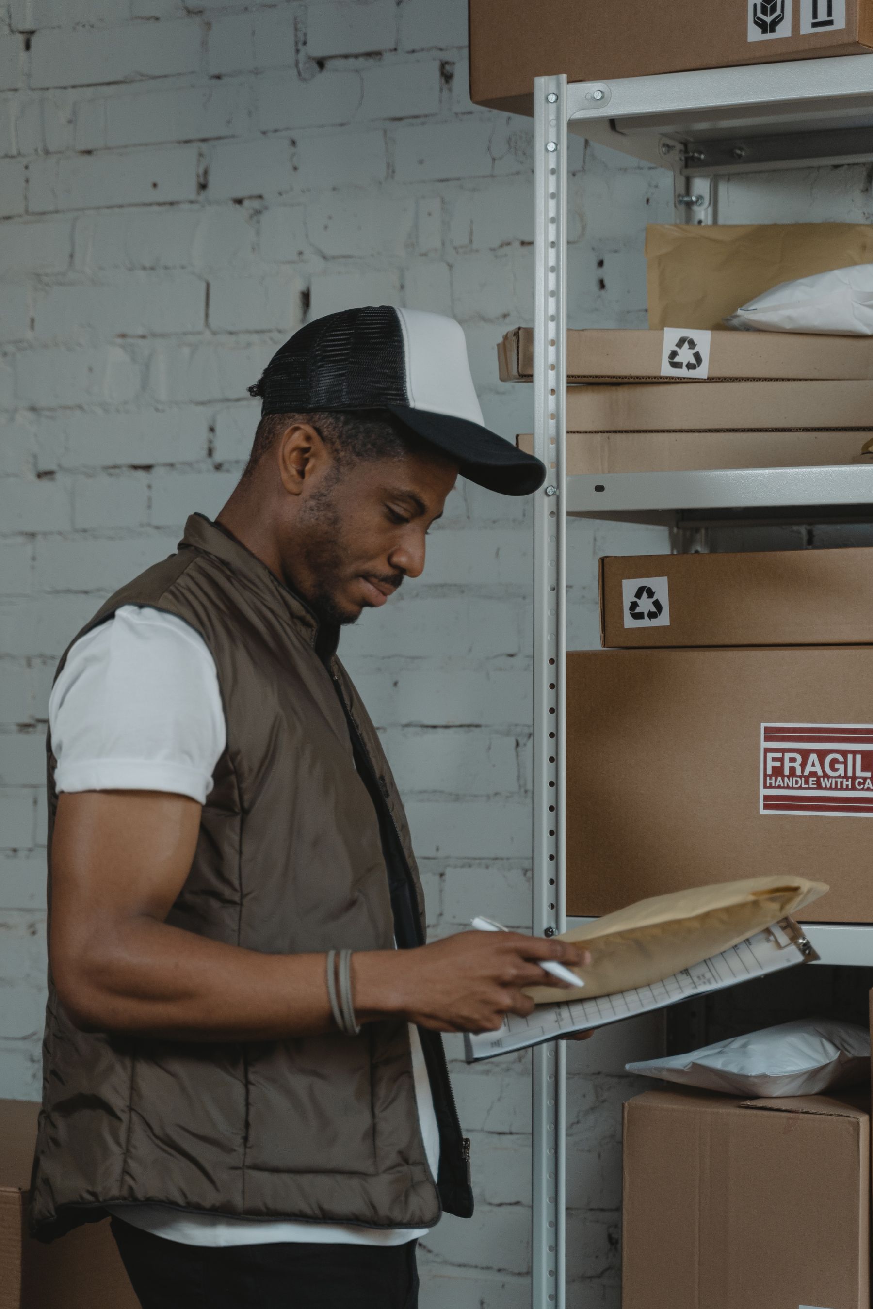 Warehouse employee checking paperwork beside shelves of boxes