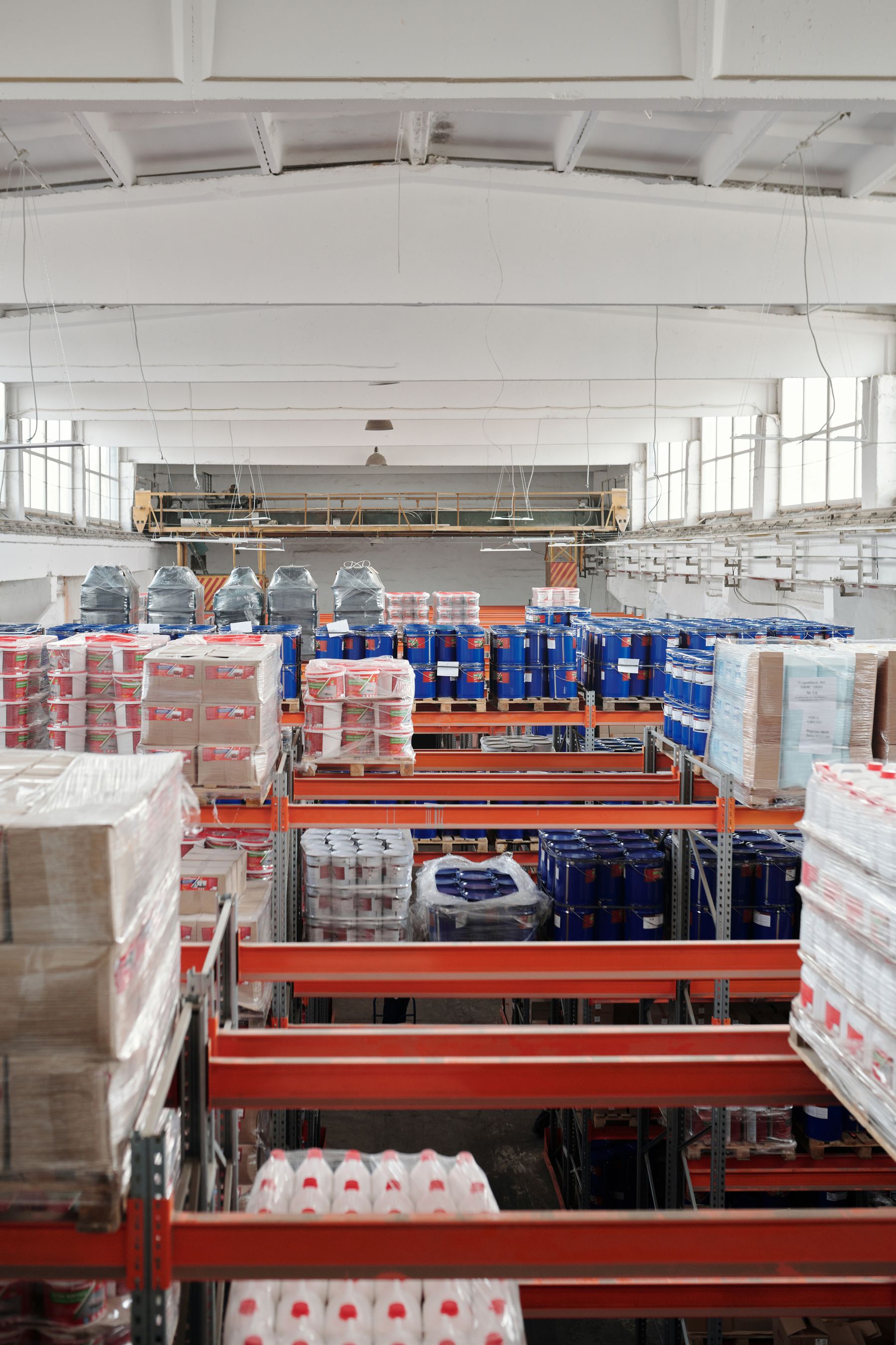 Tall warehouse racks holding pallets, cartons and stored goods